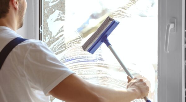 Young man washing window in office